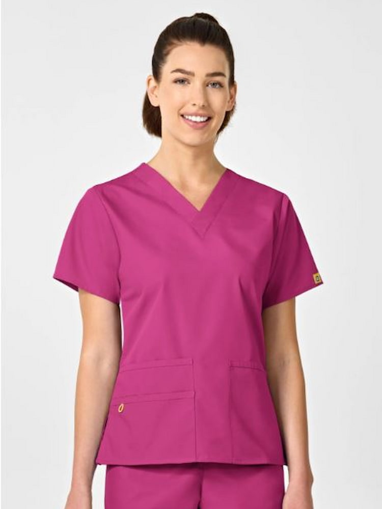 A young female pediatric nurse wearing a WonderWink Origins Women's Bravo Scrub Top in Hot Pink size XL featuring a modern fit.