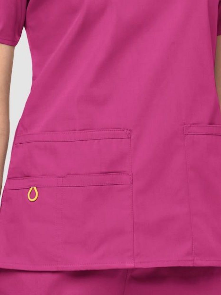 An up close image of the two lower front patch pockets on the WonderWink Origins Women's Bravo Scrub Top in Hot Pink size XL.