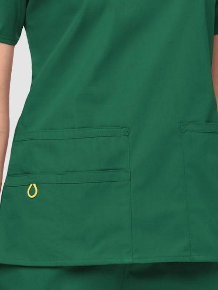 An up close image of the WonderWink Origins Women's Bravo Scrub Top in Hunter Green size 3XL featuring a total of 5 pockets.