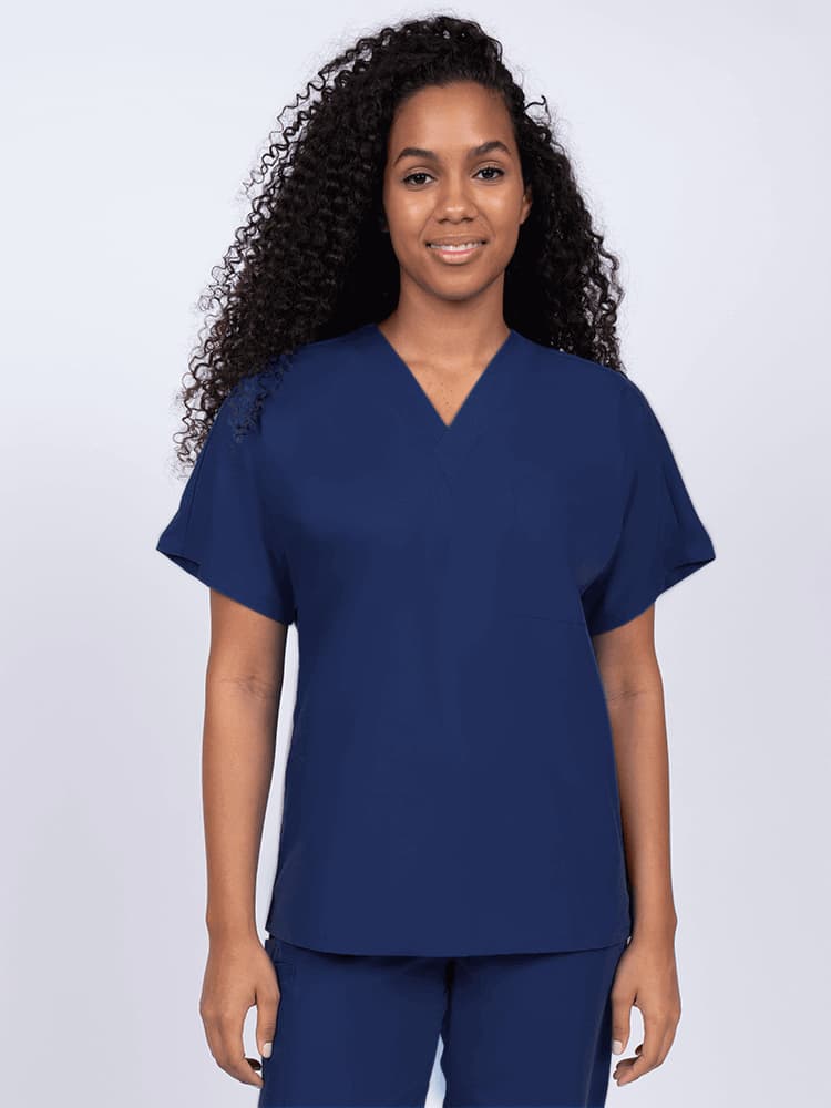 Young female Home Health Aide wearing a Luv Scrubs Unisex Single Pocket Scrub Top in Navy featuring a V-neckline.