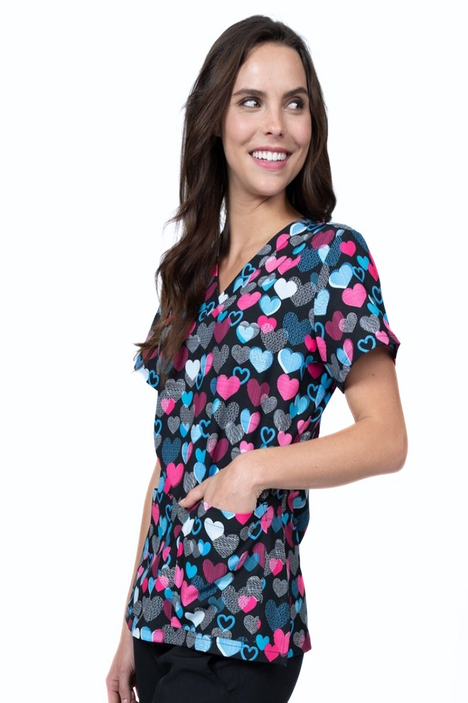 A female LPN wearing a Women's Print Scrub Top from Meraki Sport in "Follow Your Heart" featuring 2 front patch pockets.