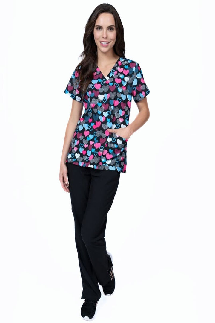 A MRI Tech wearing a Meraki Sport Women's Print Scrub Top in Follow Your Heart print size XS.