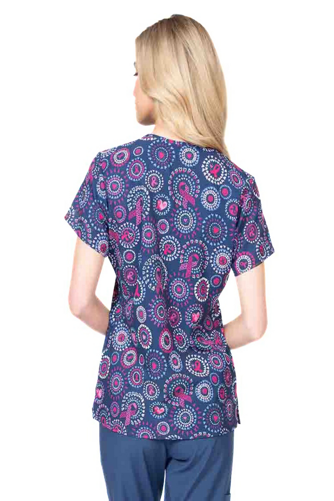 A young lady nurse wearing a Meraki Sport Women's Print Scrub Top in "Girl Power" featuring shoulder yokes & side slits for additional range of motion.