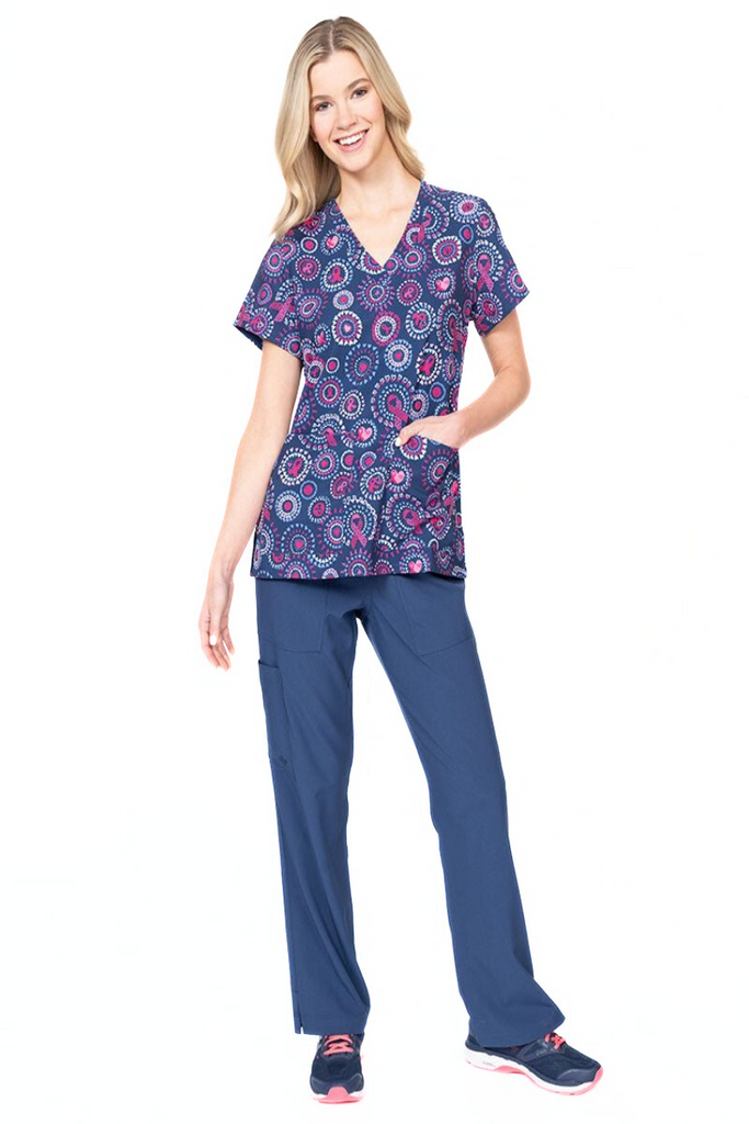 A female LPN wearing a Women's Print Scrub Top from Meraki Sport in "Girl Power" featuring 2 front patch pockets.