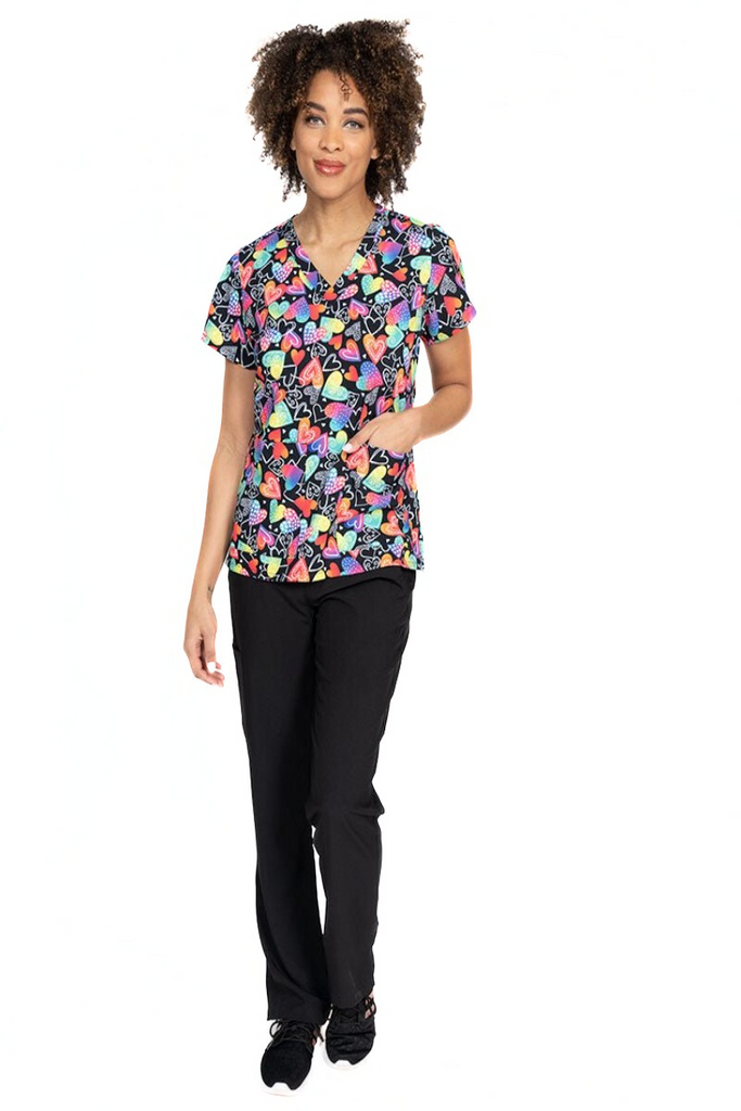 A female LPN wearing a Women's Print Scrub Top from Meraki Sport in "Wild at Heart" featuring 2 front patch pockets.