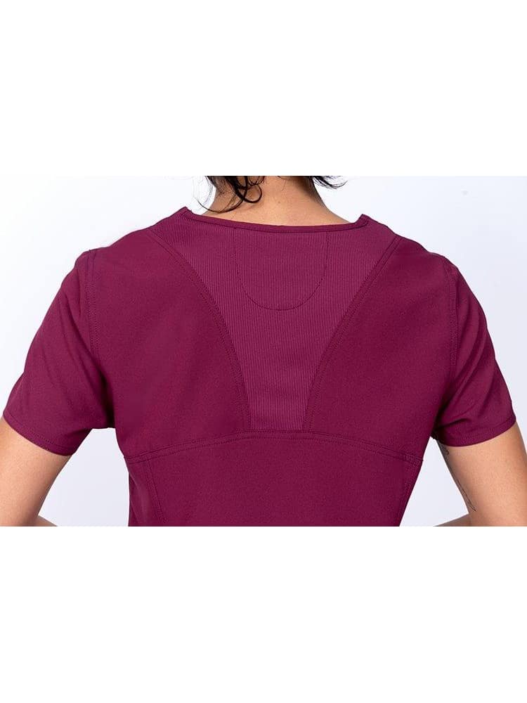 An image of the back of a Meraki Sport Women's V-neck Scrub Top in Wine size Small featuring  a center back stretch panel to provide a comfortable, and flattering fit.