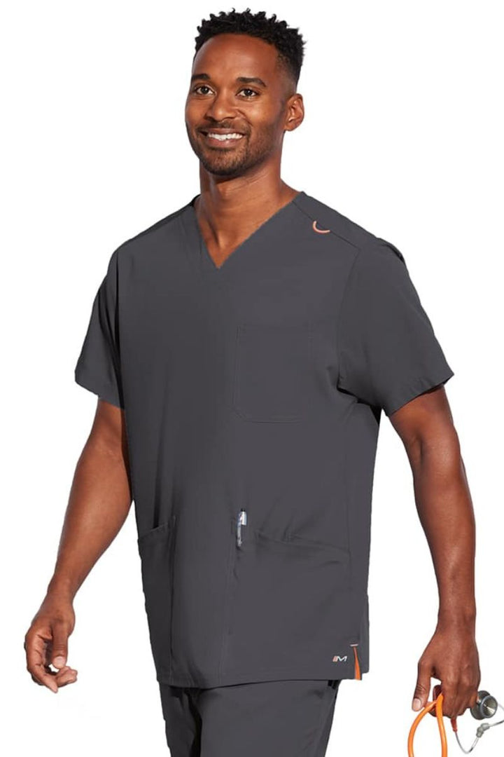 A young male Nurse wearing a Barco Motion Unisex V-neck Scrub Top in Pewter size Medium featuring a v-neckline with lap over styling.