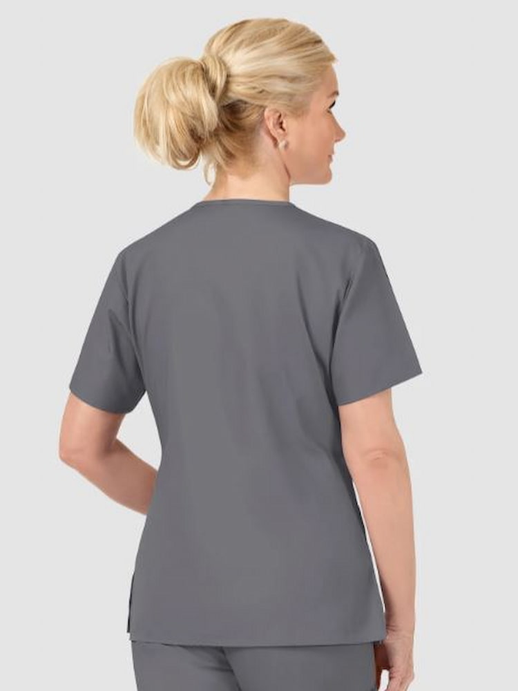 A middle aged female Pharmacist wearing a WonderWink Origins Women's V-neck Scrub Top in Pewter size XS featuring side vnets for additional mobility throughout the day.