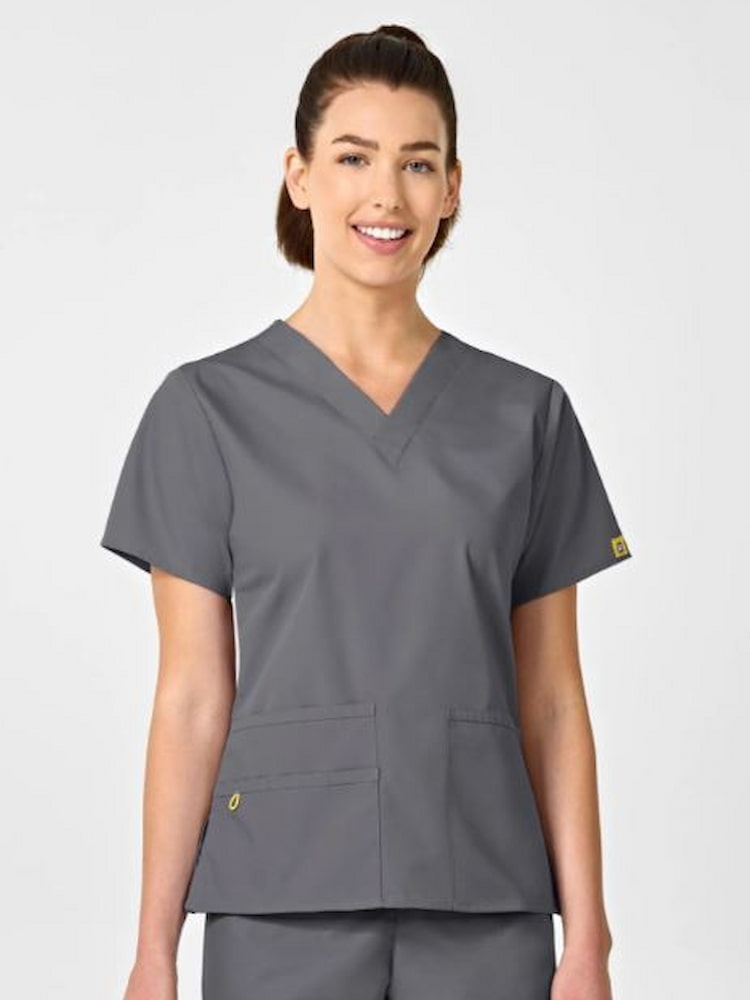 A young female Clincal Lab Tehnincian wearing a WonderWink Origins Women's Bravo Scrub Top in Pewter size Medium featuring a modern fit & v-neckline.