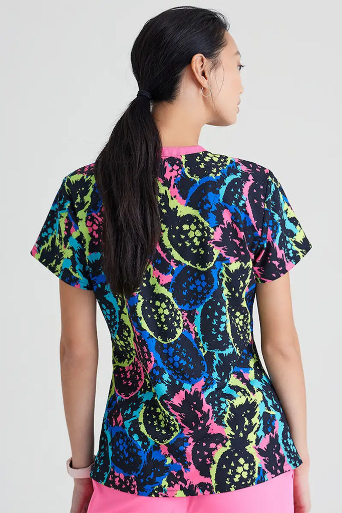 A young female children's nurse showcasing the back of the Skechers Women's V-Neck Scrub Top in Pineapple Pop featuring a center back length of 26".