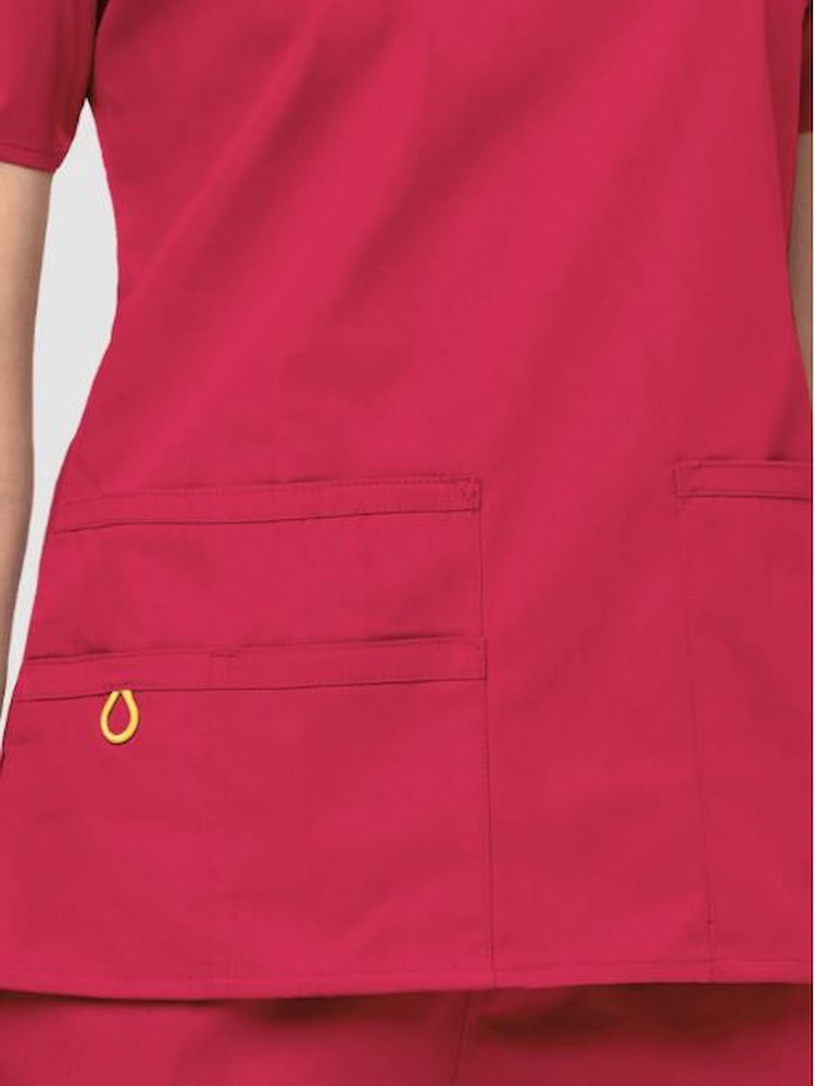 An up close image of the two lower pockets including one WonderWink signature triple pocket with hidden mesh pocket & signature ID bungee loop on the WonderWink Origins Women's Bravo V-neck Scrub Top in Red size Large.