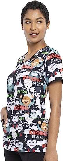 A young female Veterinarian waering a Cherokee Tooniforms Women's V-neck Print Scrub Top in "Beware of Monsters" size Xl featuring 2 front patch pockets.