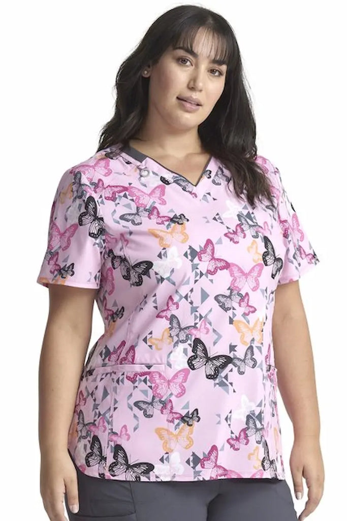 A young female Labor and Delivery Nurse wearing a Cherokee Infinity Women's V-neck Printed Scrub Top in "Geo Flutter" size Small featuring a soft and breathable fabric made of 92% Polyester and 8% Spandex.