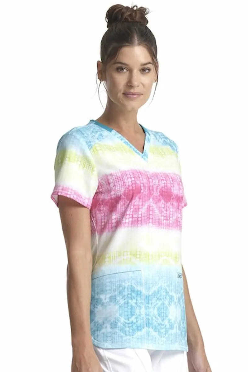 A young female Labor and Delivery Nurse wearing a Cherokee Women's V-neck Printed Scrub Top in "Trippy Stripes" size XL featuring two front patch pockets that provide ample storage space.