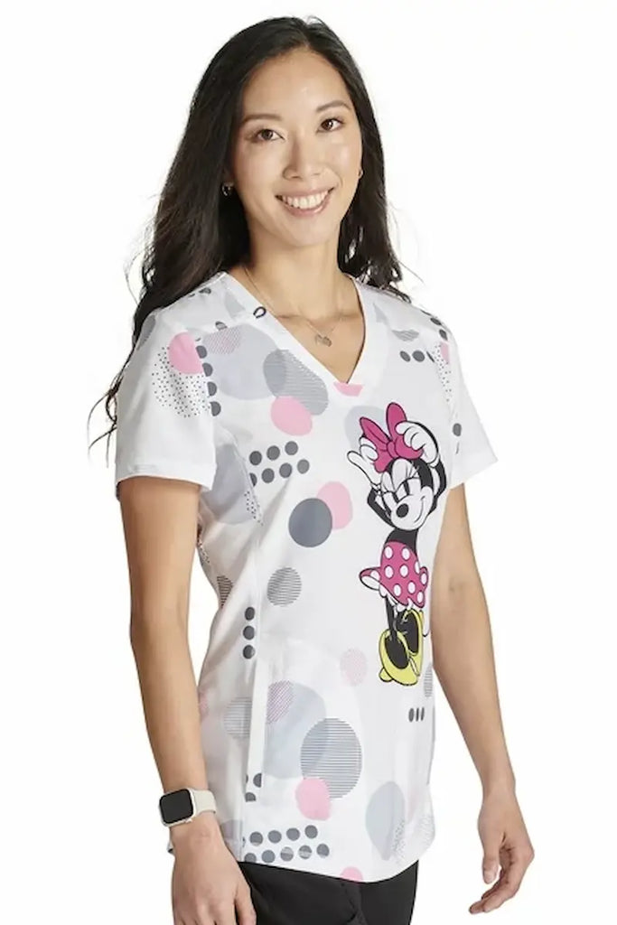 A young female LPN wearing a Tooniforms Women's Printed V-neck Scrub Top in "Running in Circles" size Medium featuring Princess seams to provide a a flattering all day fit.