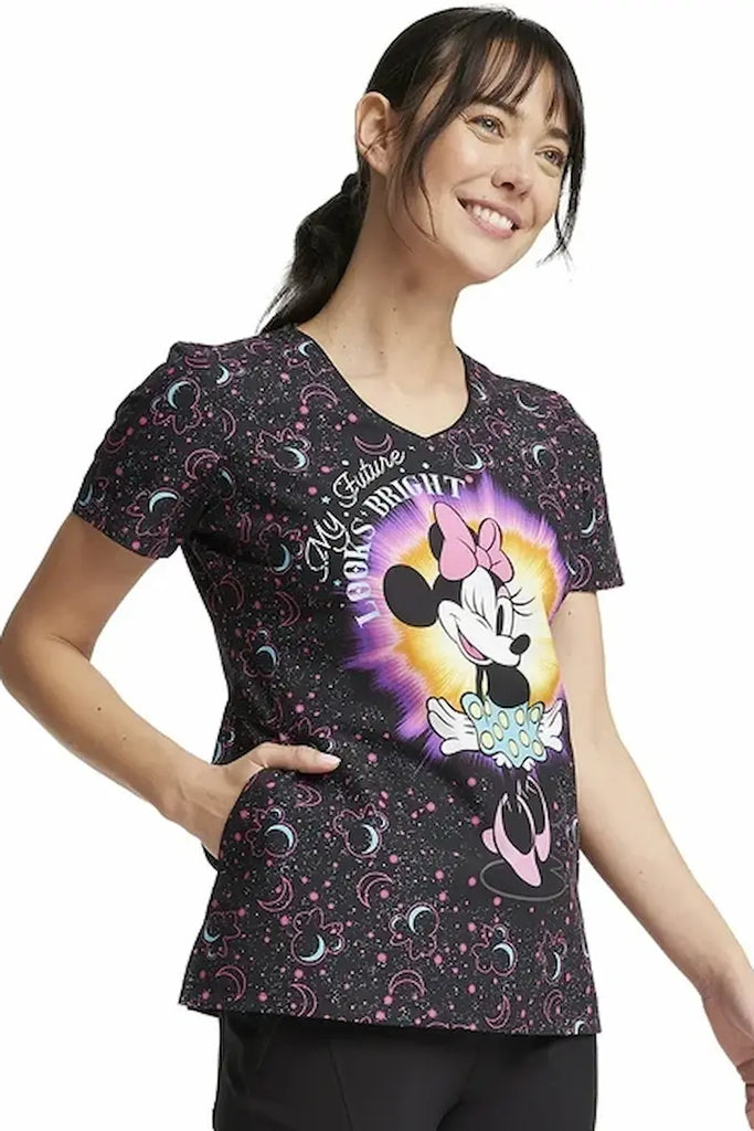 A young female Labor and Delivery Nurse wearing a Tooniforms Women's V-neck Print Scrub Top in "My Bright Future" size Large featuring Disney's "Minnie Mouse" with an inspiring "My Bright Future" design, injecting a touch of positive energy and optimism into your workday. 