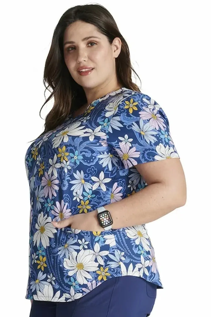 A young female Neonatal Nurse wearing a Cherokee Women's V-neck Printed Scrub Top in "Prairie Paisley" size Large featuring two front patch pockets for ample storage space.