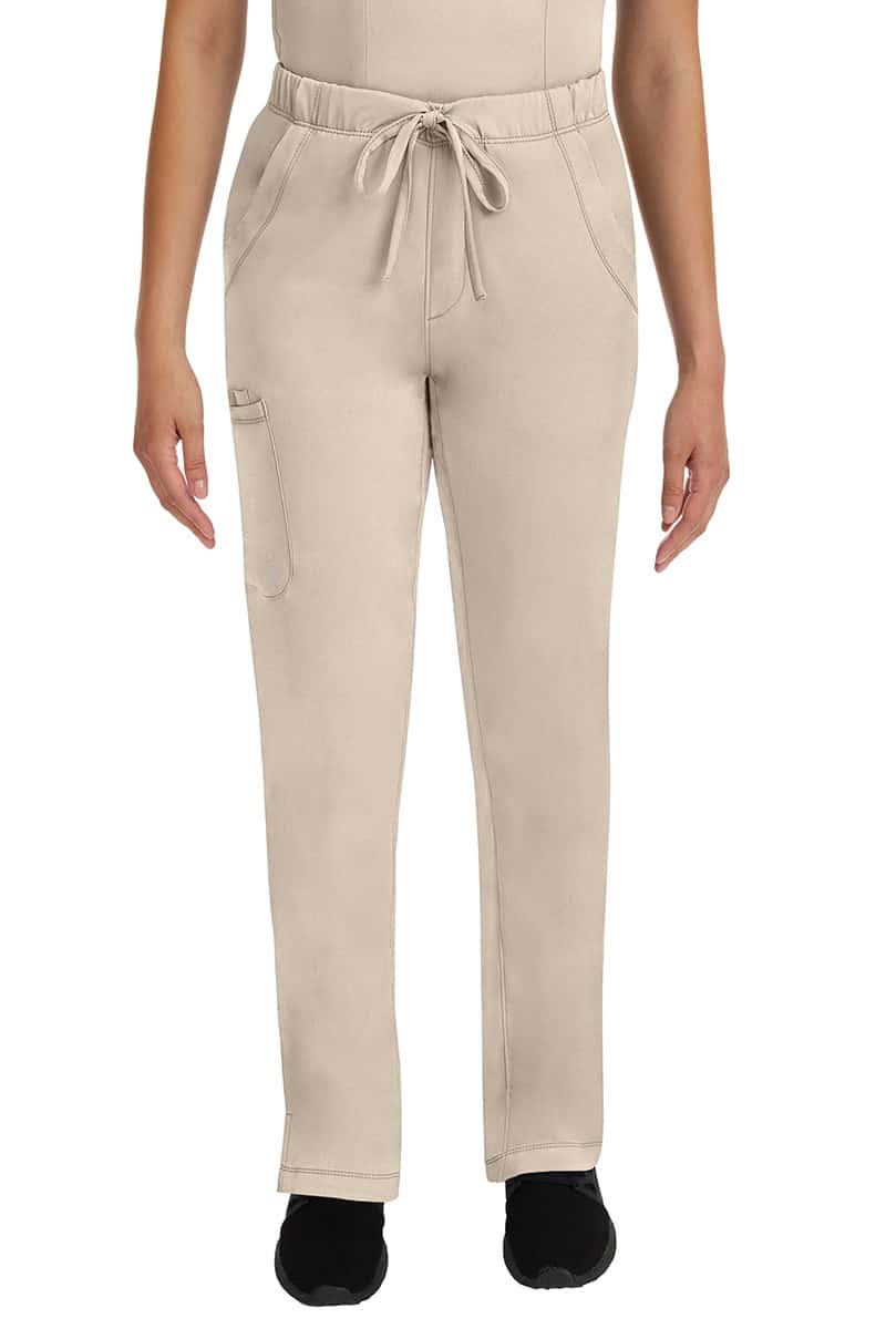 A young lady LPN wearing an HH Works Women's Rebecca Multi-Pocket Drawstring Pant in Khaki featuring n all elastic waistband with a drawstring tie front.
