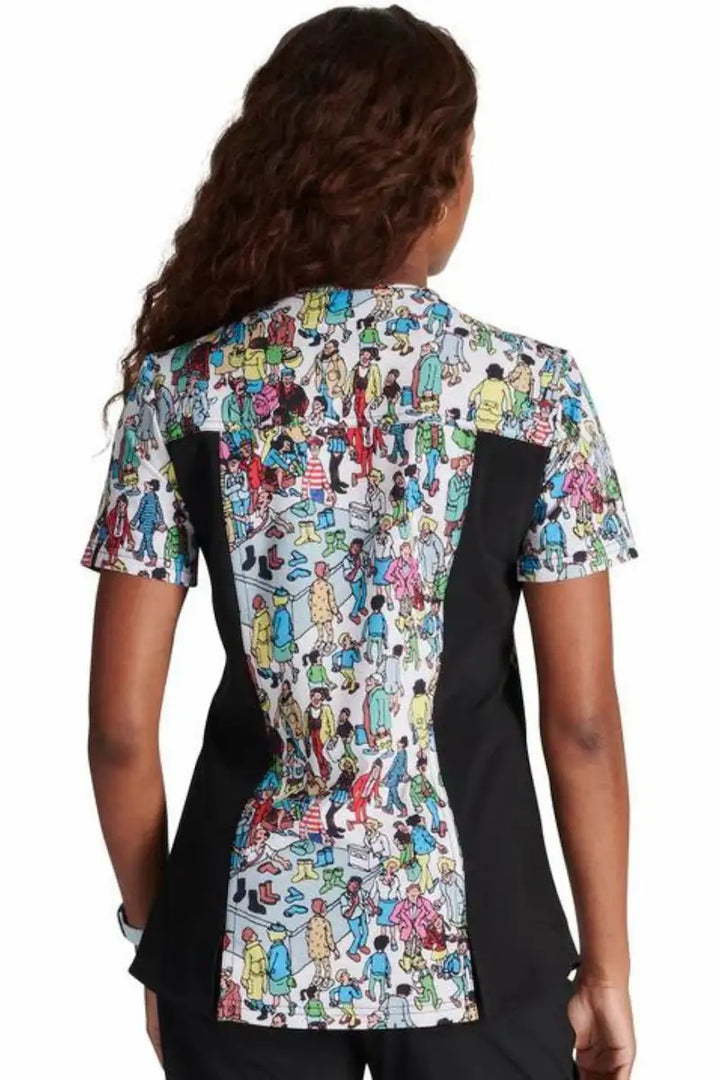 A young nurse showcasing the back of the "Where's Waldo" Tooniforms Women's V-Neck Print Scrub Top in size medium featuring a center back length of 26".