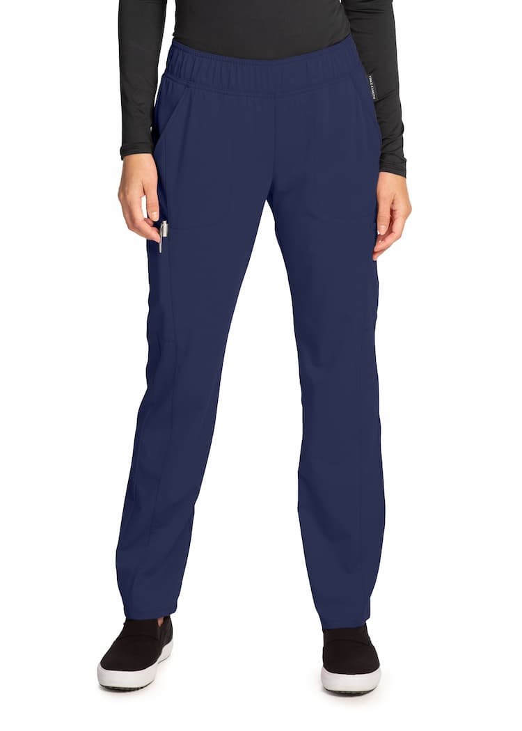 An image of a young female Surgical Assistant wearing a Vince Camuto Women's Mid Rise Pull-On Pant in Navy size XS featuring criss-cross vents to provide a cool and comfortable all day fit. 
