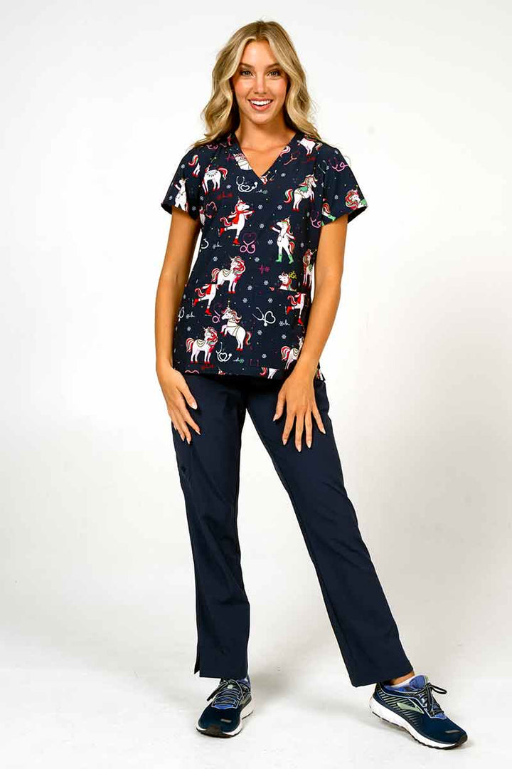 A female LPN wearing a Women's Print Scrub Top from Meraki Sport in "Jolly Nursicorn" size medium featuring 2 front patch pockets.