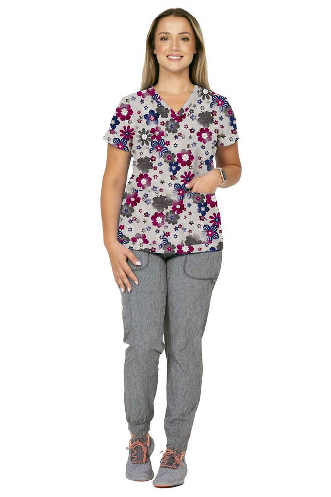 A female LPN wearing a Women's Print Scrub Top from Meraki Sport in "Splash of Heather" size medium featuring 2 front patch pockets.