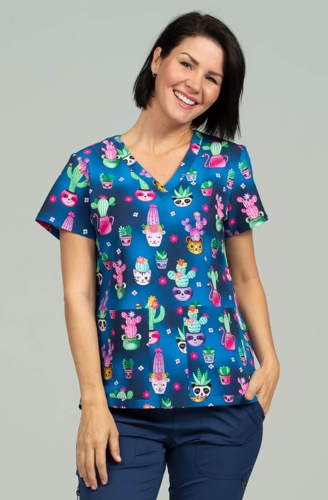 A young female Medical Assistant wearing a Meraki Sport Women's Print Scrub Top in "Stuck on You" size Medium featuring a v-neckline & short sleeves.