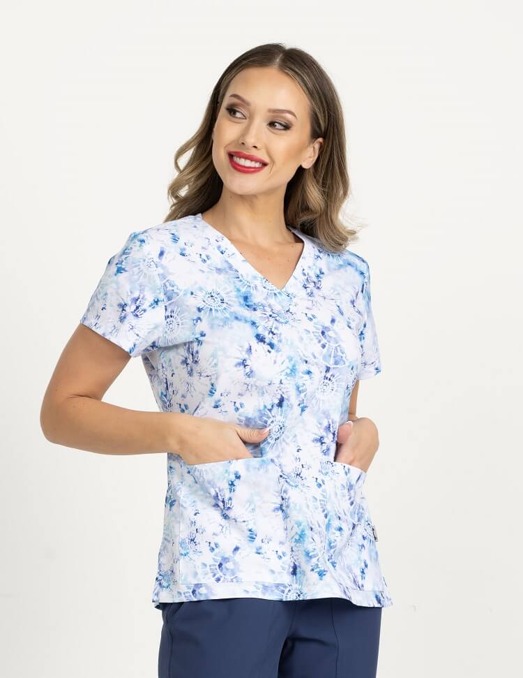 A young female Physical Therapist wearing a Meraki Sport Women's Print Scrub Top in "Tie Dye Obsession" size Medium featuring a v-neckline & short sleeves.