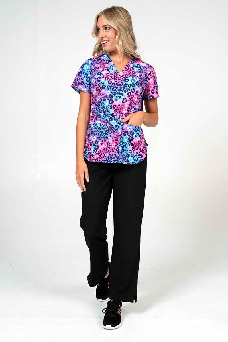 Young female nurse wearing a Meraki Sport Women's Print Scrub Top in "Wild One" size XL featuring side slits for additional range of motion.