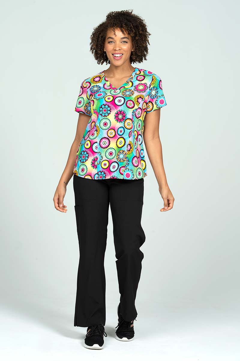 A full body image of a young female LPN wearing a Meraki Sport Women's Print Scrub Top in size Small featuring shoulder yokes for shaping & side slits for additional range of motion.