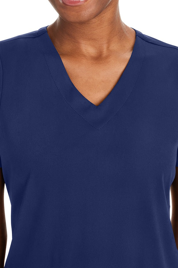A female physical therapist wearing a Purple Label Women's Andes Curved V-Neck Scrub Top in "Navy" size 2XL featuring a curved V-neckline.