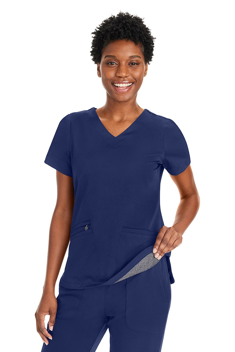 A young female LPN wearing a Purple Label Women's Andes Curved V-Neck Scrub Top in "Navy" size XL featuring a luxurious 4-way stretch fabric.