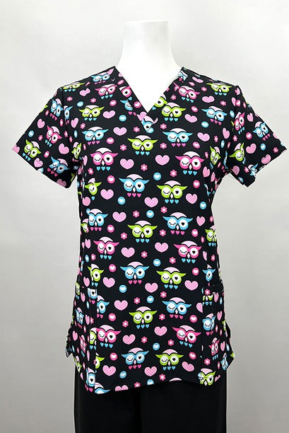 A frontward facing image of the Revel Women's V-Neck Print Scrub Top in "Owl Heart" size Medium featuring a total of 3 pockets & a contemporary fit.