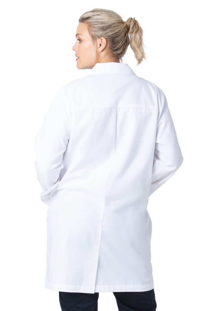 A young female Chemist wearing a Landau Women's 3-Pocket Button Front Lab Coat in White Sanded size XL featuring a back yoke for a flattering drape.