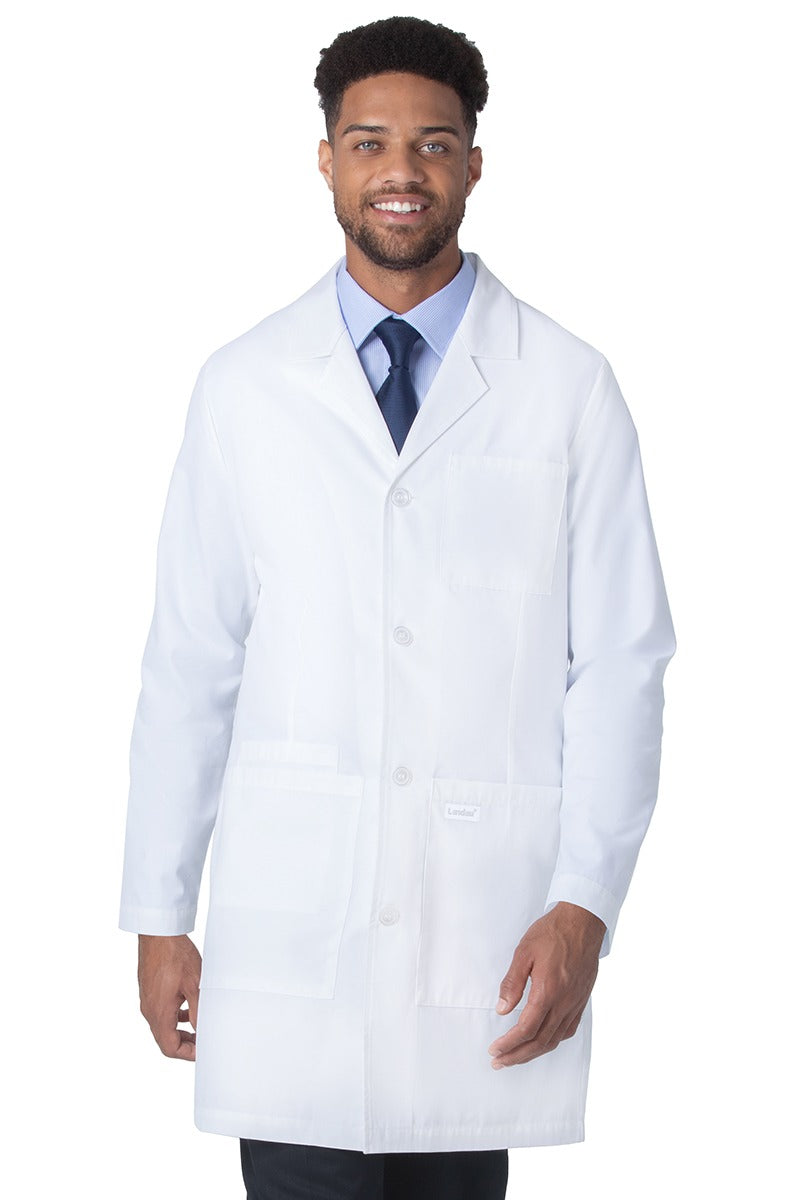 A young male Doctor wearing a Landau Unisex 4-Pocket Mid-Length Lab Coat in White Sanded size 2XL featuring a 4 button closure on the front.