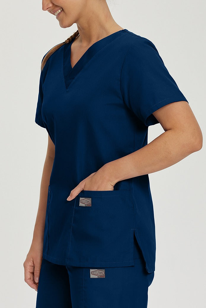 A young female Phlebotomist wearing a Landau ScrubZone Women's V-Neck Scrub Top in True Navy size Small featuring 2 front patch pockets.