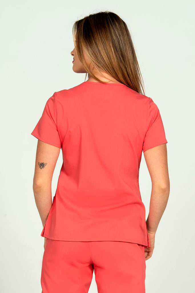 Woman wearing an Epic by MedWorks Women's Y-Neck Scrub Top in Coral with a center back length of 26".