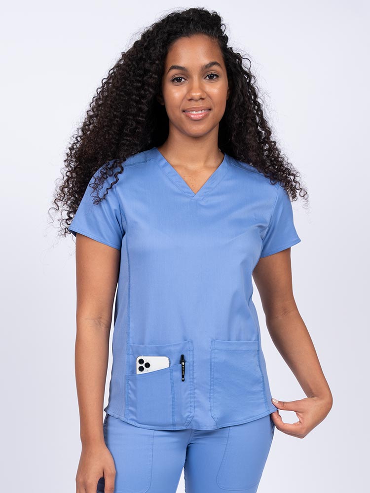 Nurse wearing an Epic by MedWorks Women's Blessed Scrub Top in ceil with a V-neckline & short sleeves.
