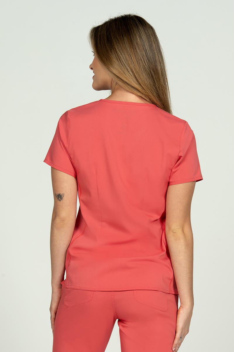 A female Nursing Assistant wearing an Epic by MedWorks Blessed Scrub Top in Coral size medium featuring a center back length of 26.5".