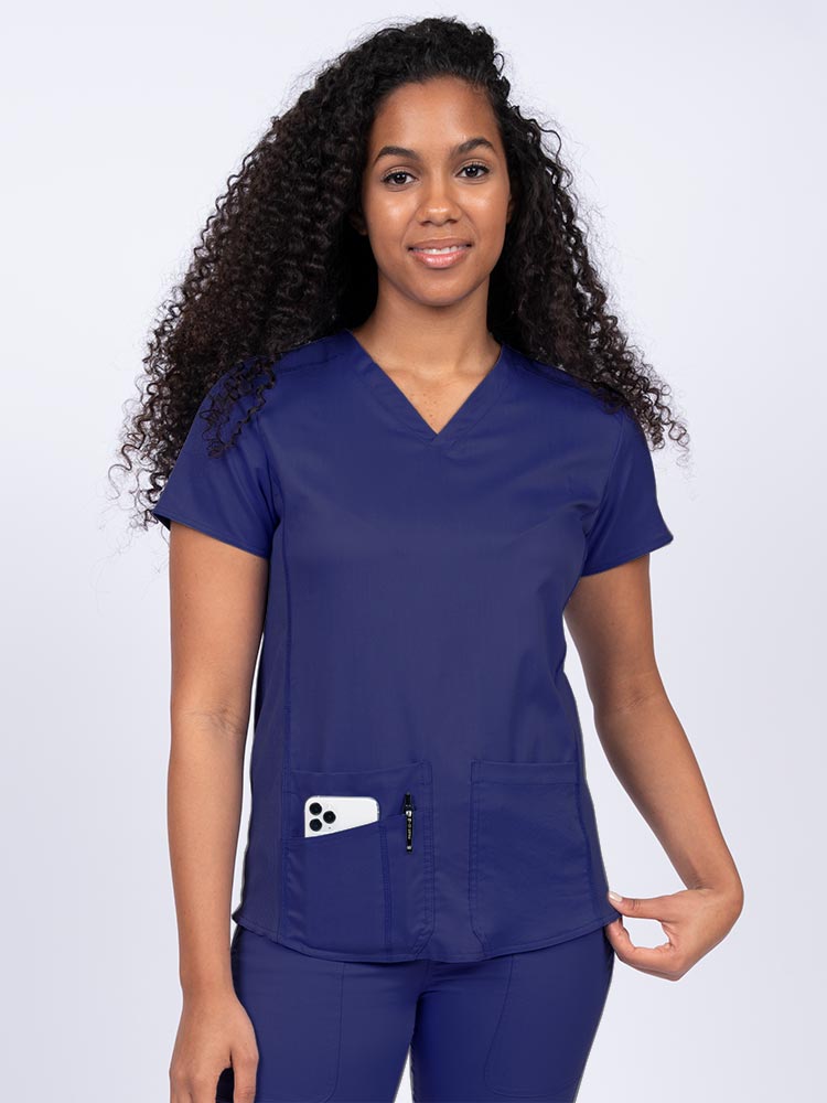 Woman wearing an Epic by MedWorks Women's Blessed Scrub Top in navy with two front patch pockets.