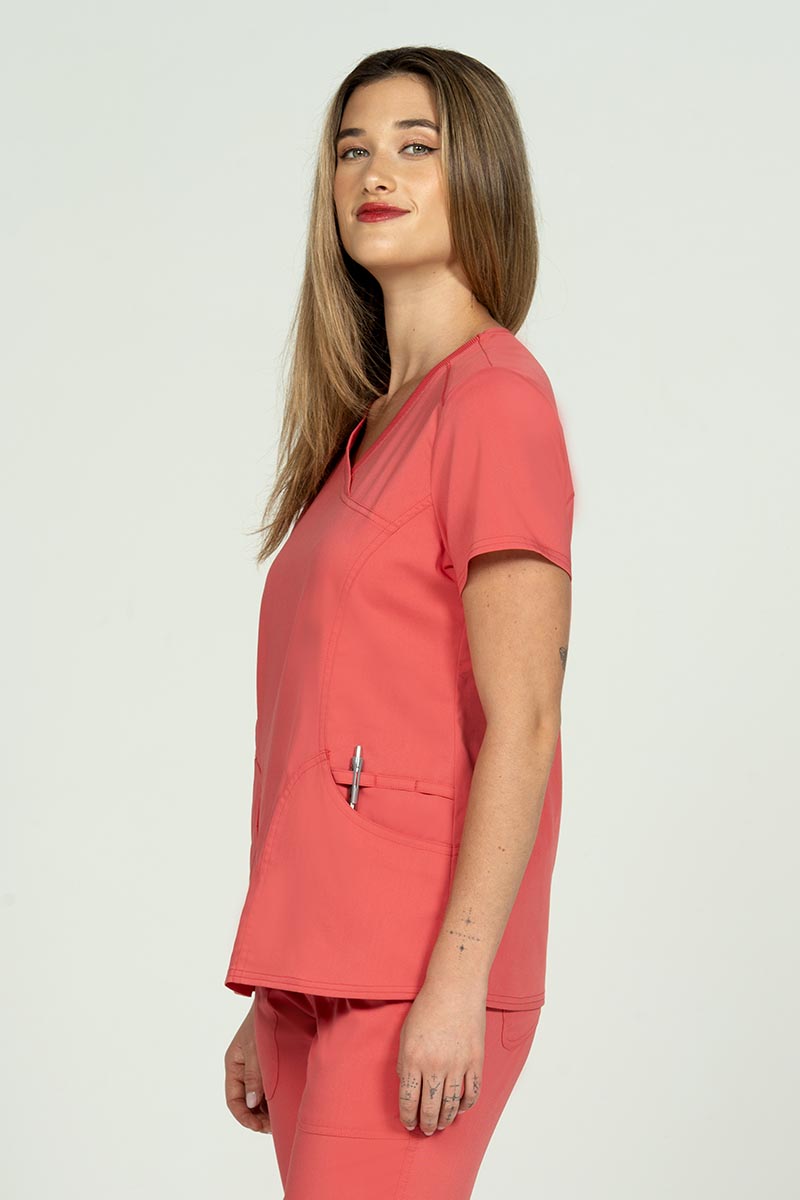 A young woman wearing an Epic by MedWorks Women's Knit Collar Mock Wrap Scrub Top in Coral featuring an easy care, 2 way stretch fabric that allows air to pass easily through the garment.