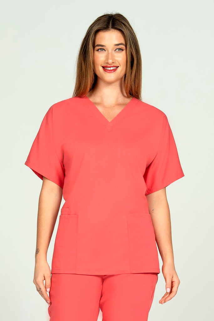 A female Dental Assistant wearing an Epic by MedWorks Unisex V-neck Scrub Top in Coral featuring a V-neckline with short sleeves. 