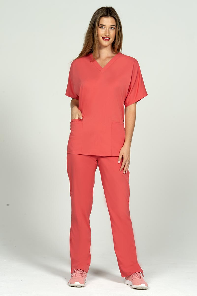 A female Radiologic Technologist wearing an Epic by MedWorks Unisex V-neck Scrub Top in Coral size small featuring a streamline fit for a tailored look without losing mobility.