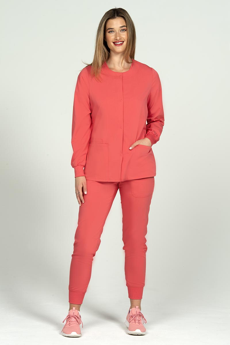 A female nurse wearing an Epic by MedWorks Women's Snap Front Scrub Jacket in Coral size XL featuring a super soft, easy care fabric designed to keep you looking and feeling great all day.