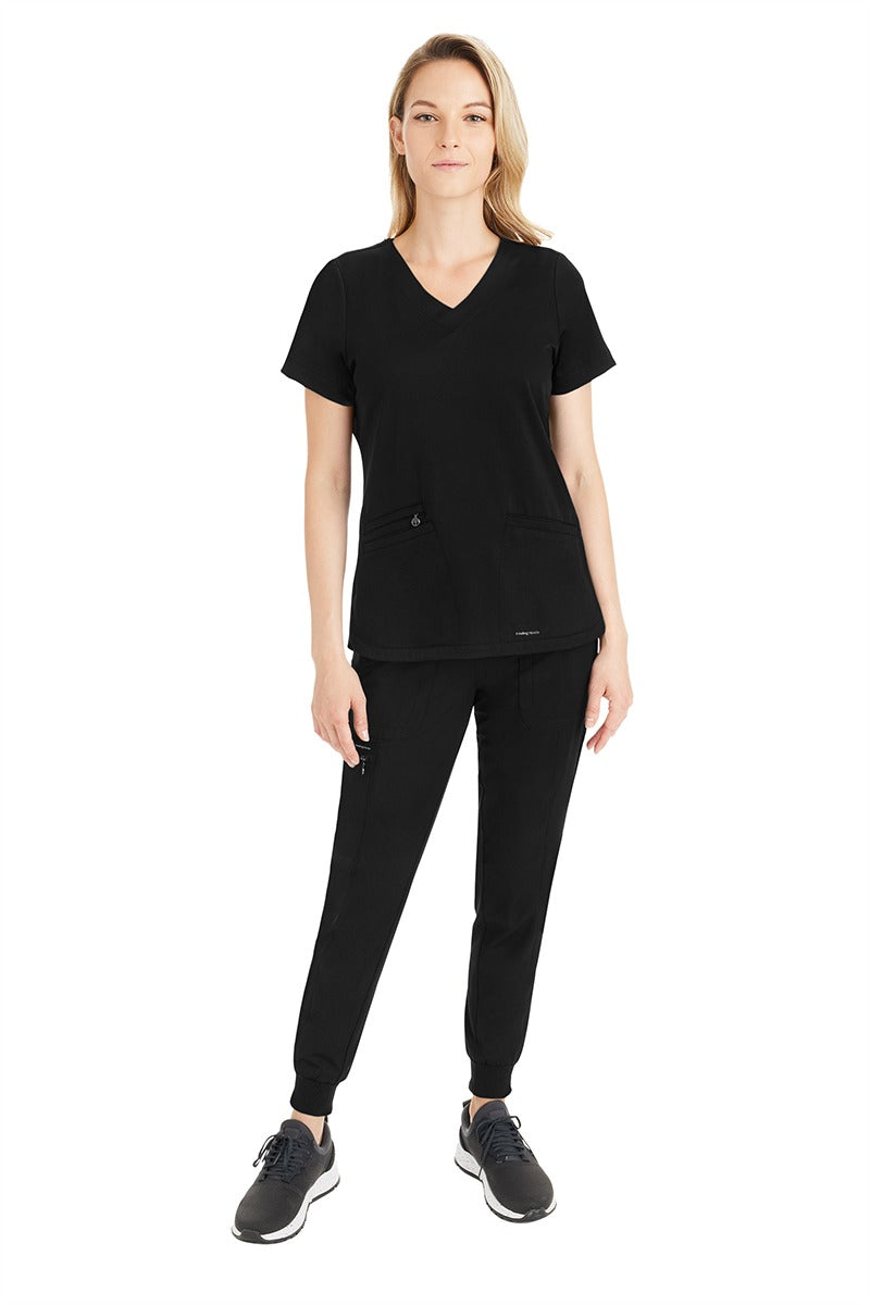 A young female Medical Assistant wearing a Purple Label by Healing Hands Women's Aspen Jogger Scrub Pant in "Black" size Small Petite.