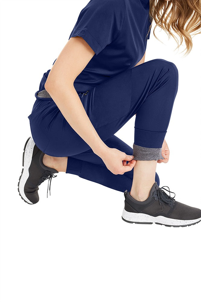 A young female Phlebotomist wearing a pair of Purple Label Women's Aspen Jogger Scrub Pants in "Navy" size XL featuring an added layer of knit fabric that feels like a warm hug.