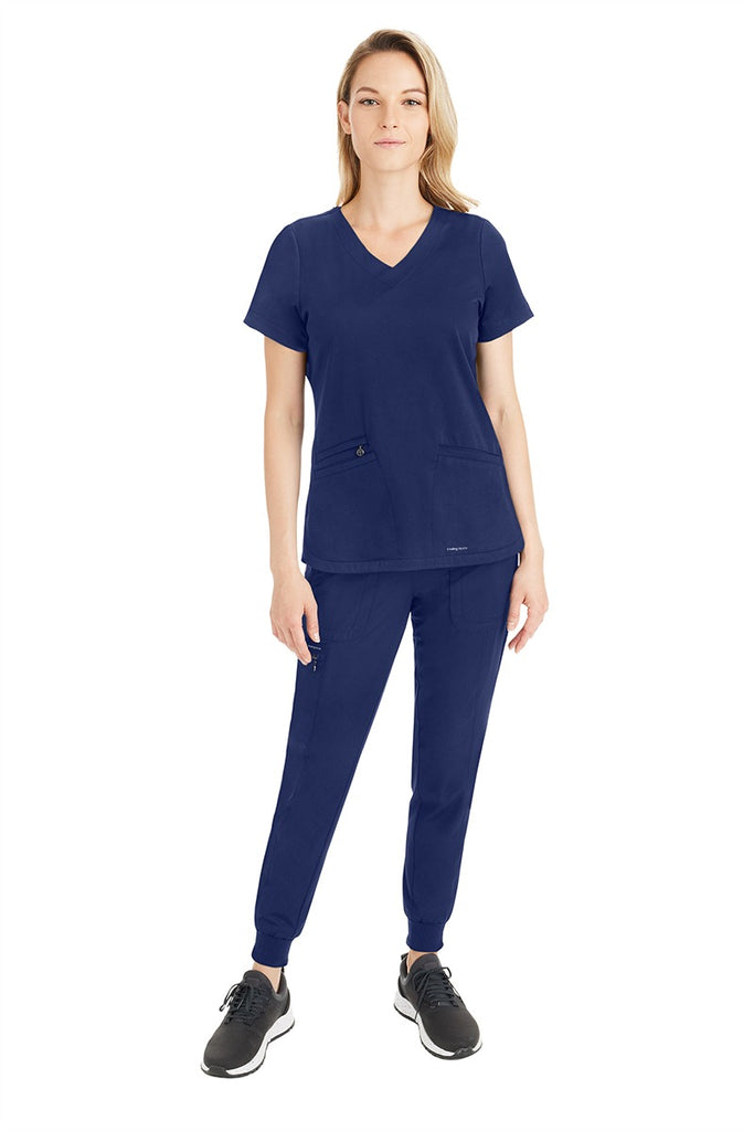A young female Medical Assistant wearing a Purple Label by Healing Hands Women's Aspen Jogger Scrub Pant in "Navy" size XS.