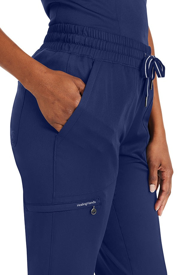 A female Nursing Assistant wearing a Purple Label Women's Knit Lined Alaskan Pant from Healing Hands in "Navy" size small featuring 2 front slash pockets.