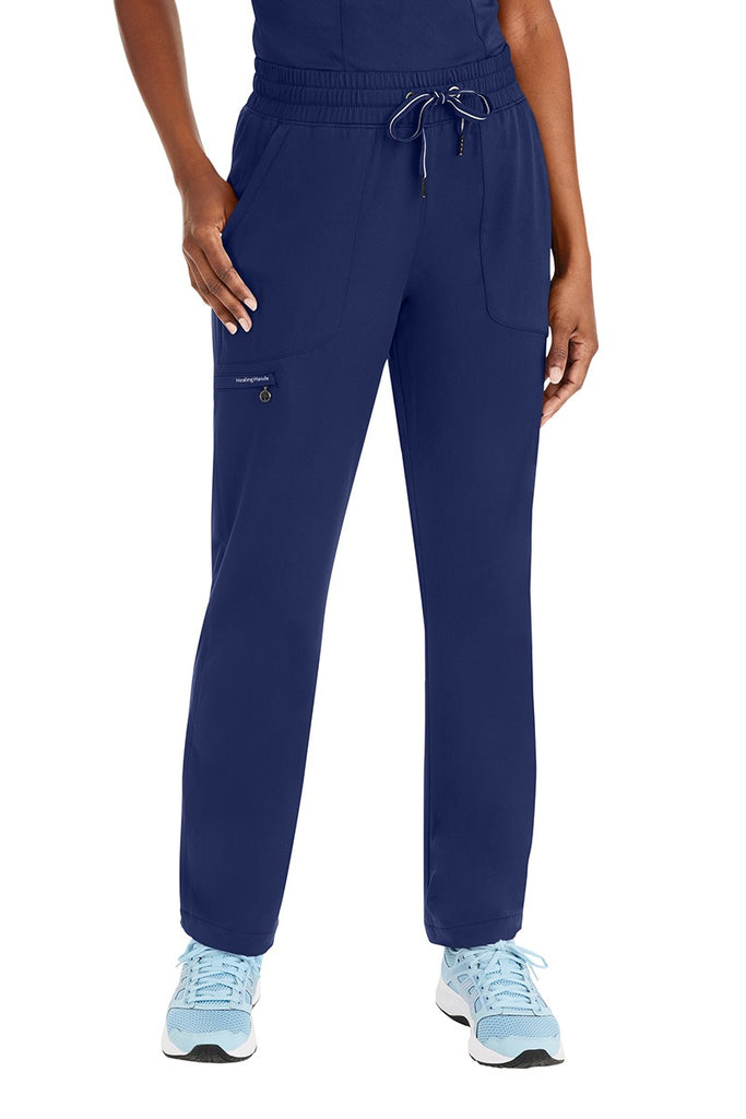 A young female Licensed Practical Nurse wearing a Purple Label Women's Knit Lined Alaskan Pant in "Navy" size XL featuring 1 zip closure cargo pocket on the wearer's right side.