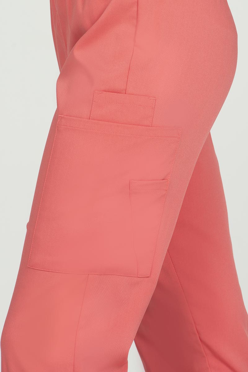 A young female Sonographer wearing an Epic by MedWorks Women's Elastic Waist Scrub Pant in Coral size medium featuring one outside pen pocket.